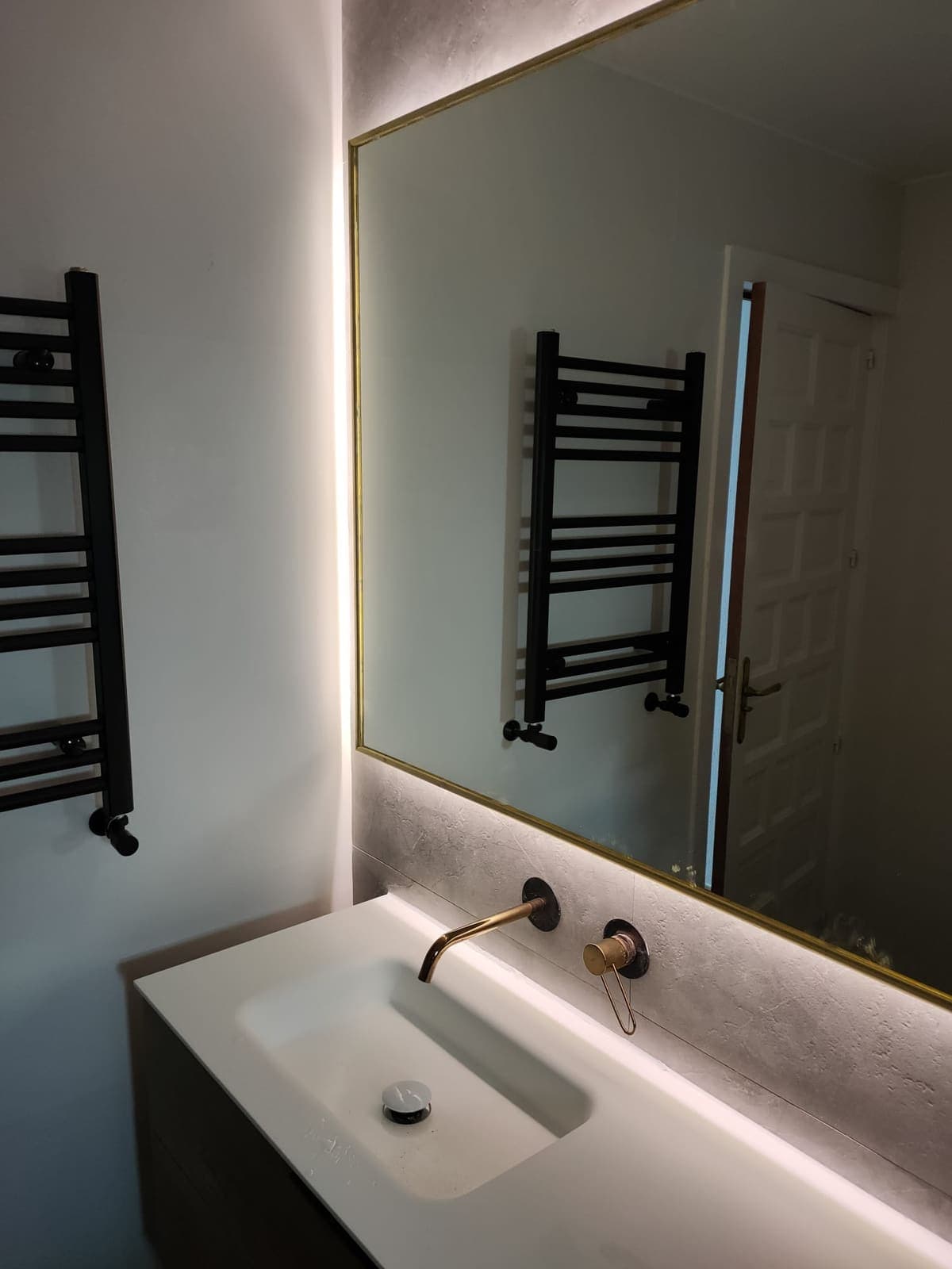 Lavabo suspendido con mueble de madera y mampara de vidrio en baño reformado en Gandía