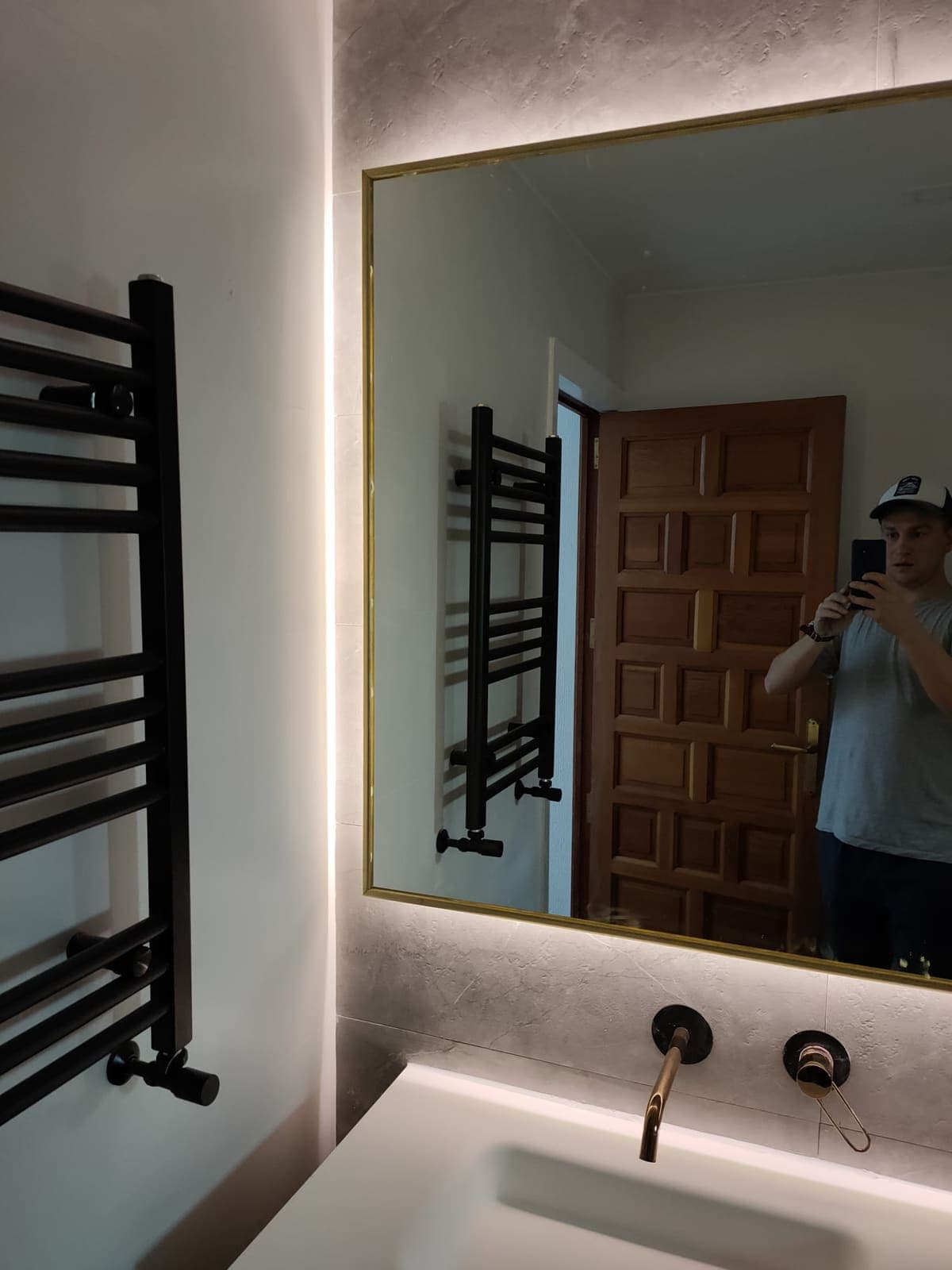 Lavabo suspendido blanco con grifo negro empotrado y toallero eléctrico
