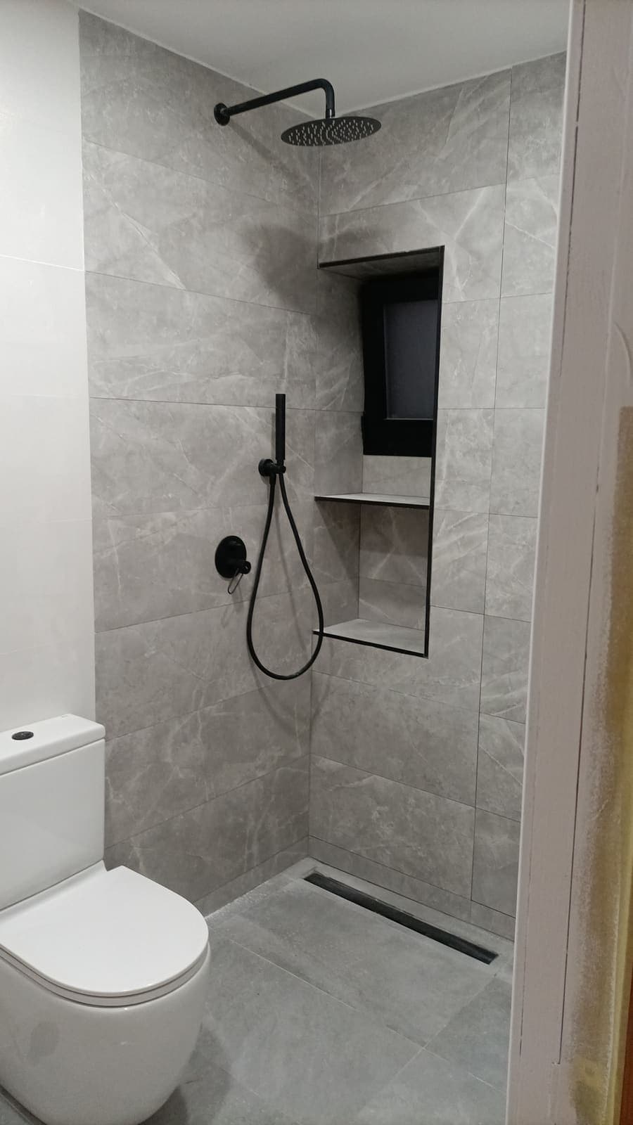 Zona de ducha de obra con hornacina integrada e inodoro suspendido