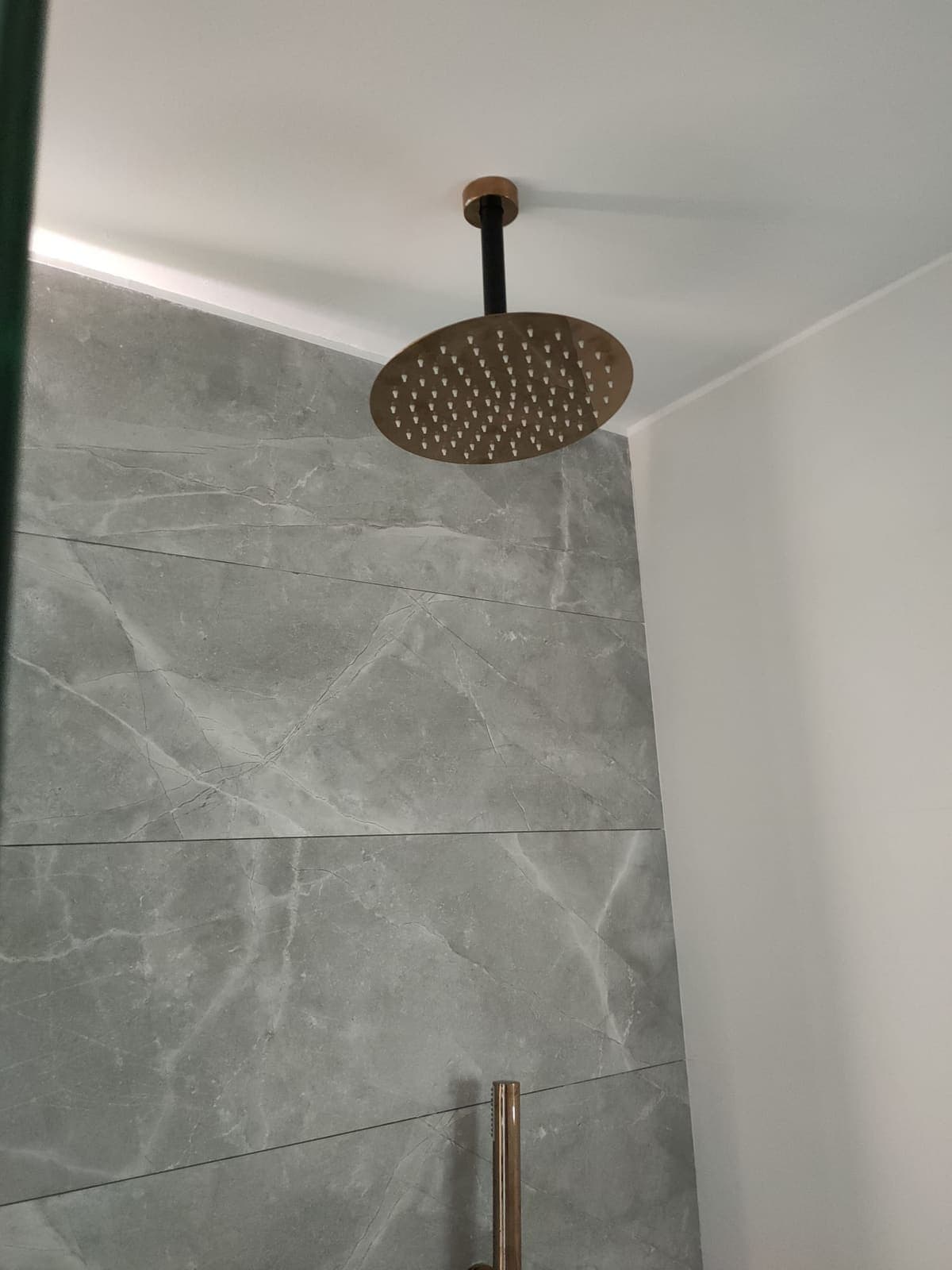 Ducha tropical empotrada en el techo sobre azulejo gris de gran formato