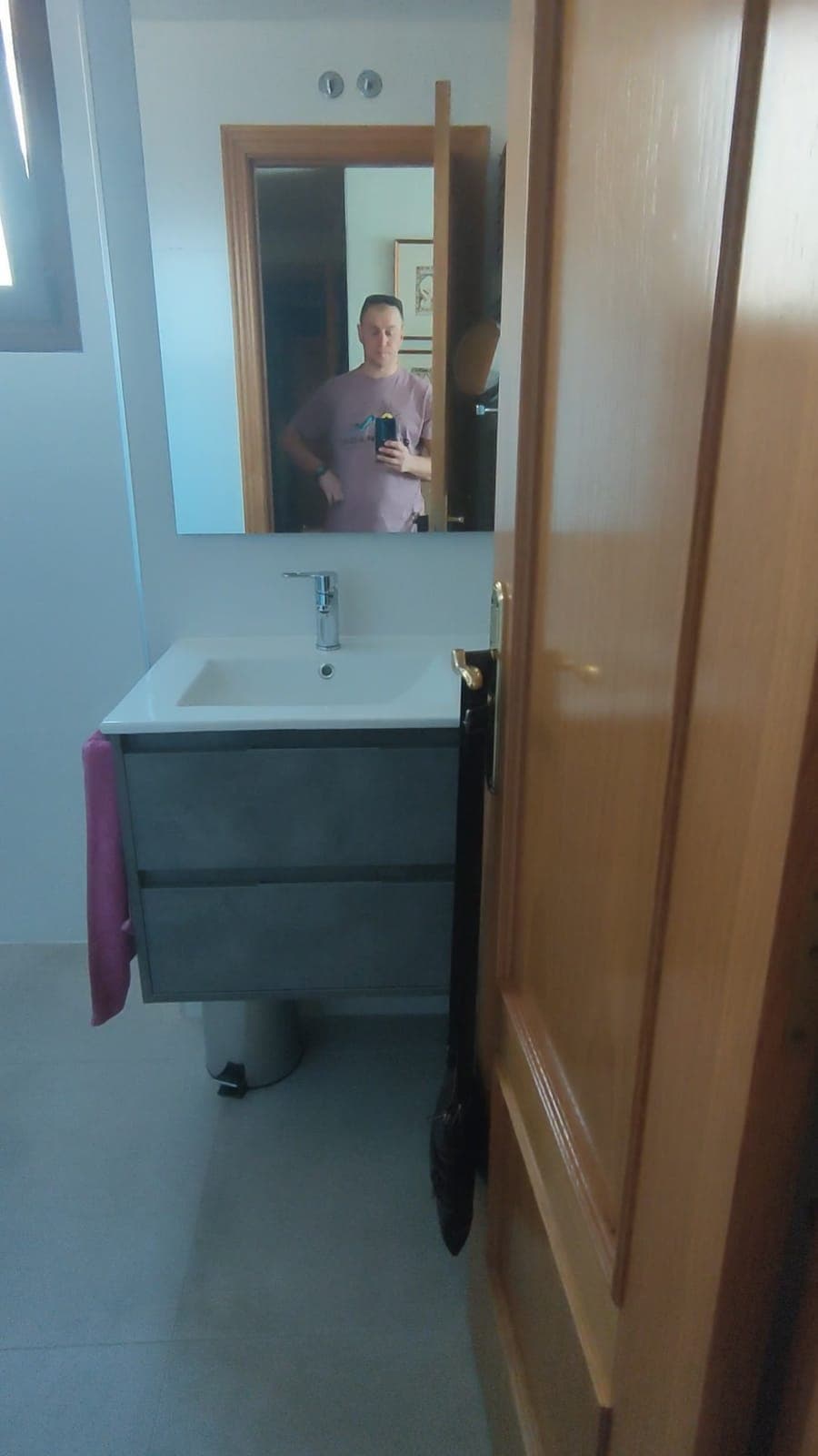 Mueble de lavabo suspendido gris con espejo en baño reformado