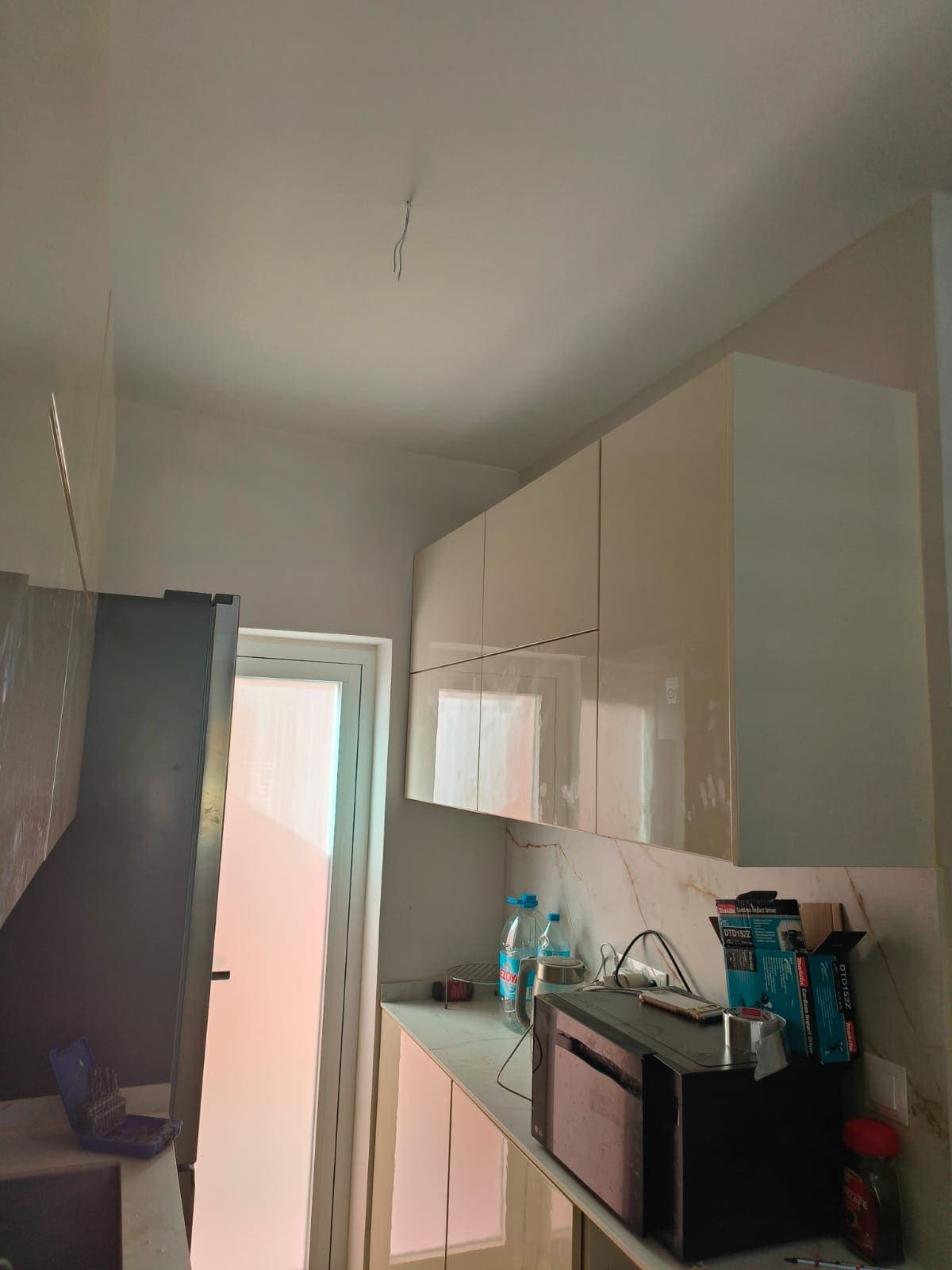 Módulos altos y columna con microondas junto a la ventana en la cocina reformada en Calpe