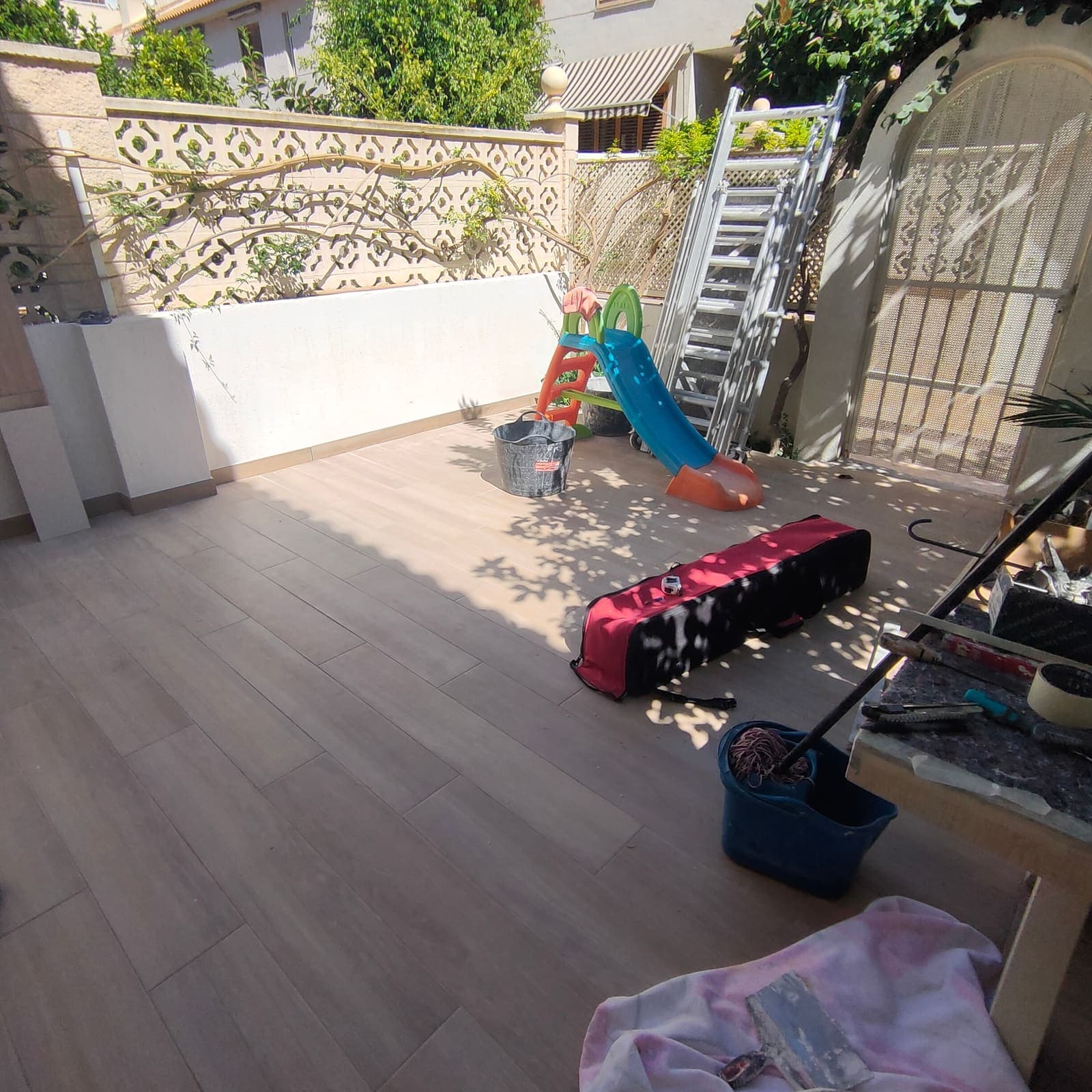 Terraza reformada vista desde el ventanal, con el muro perimetral enfoscado y pintado