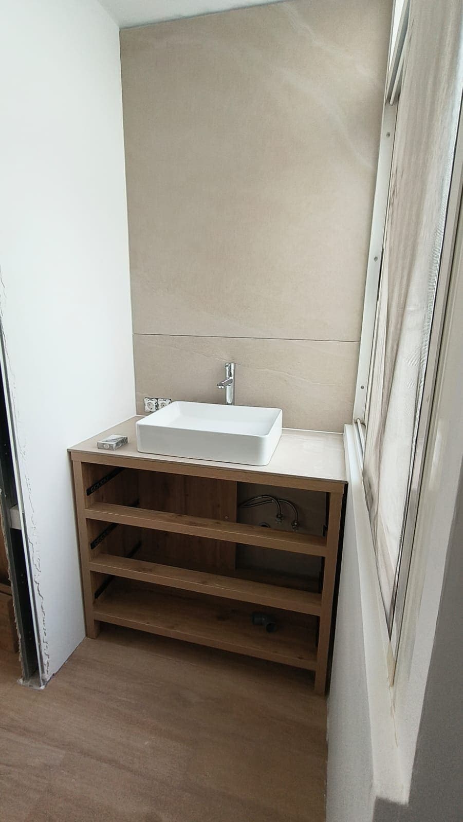 Mueble de lavabo de madera con lavabo sobre encimera en el aseo reformado
