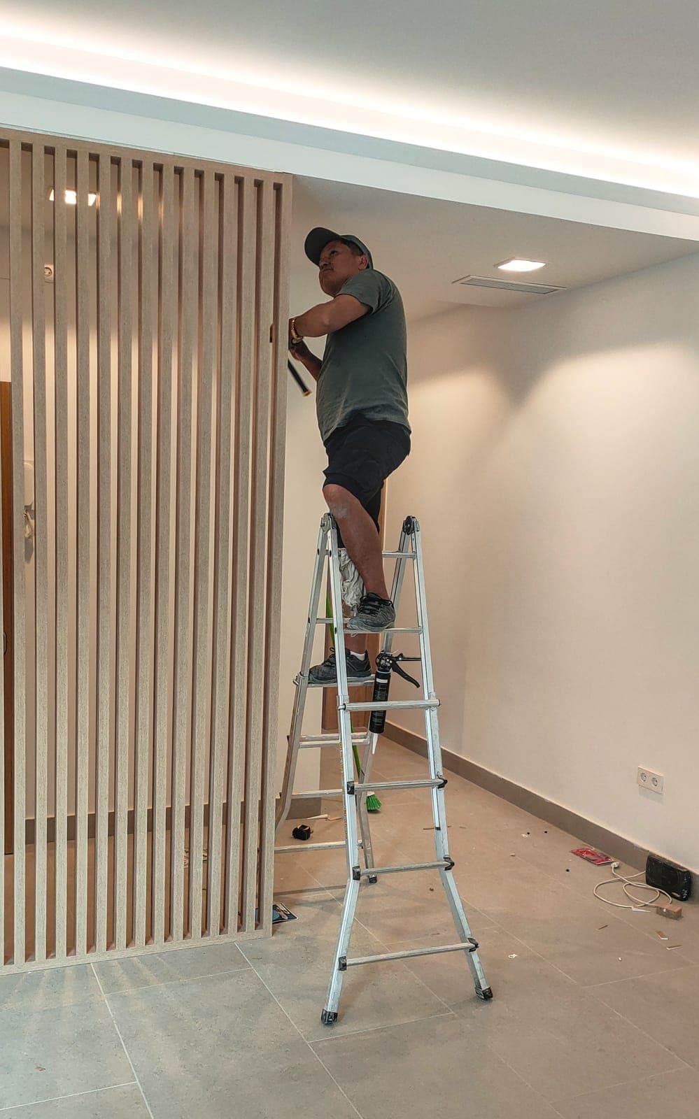 Yuriy, propietario de KAS Reformas, instalando un revestimiento de lamas de madera subido a una escalera