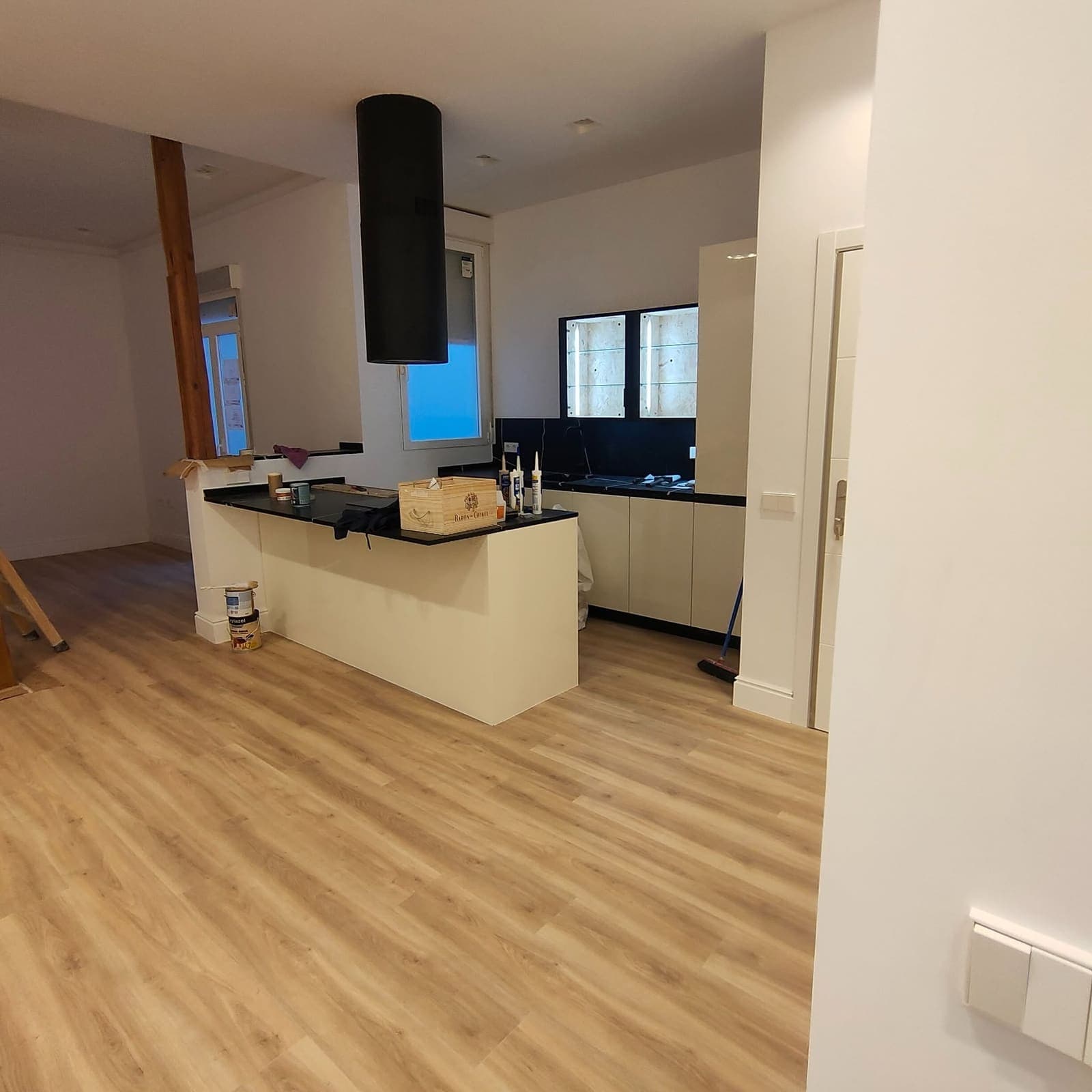 Cocina abierta al salón con isla central, encimera negra y campana de techo instalada por KAS Reformas en Calpe
