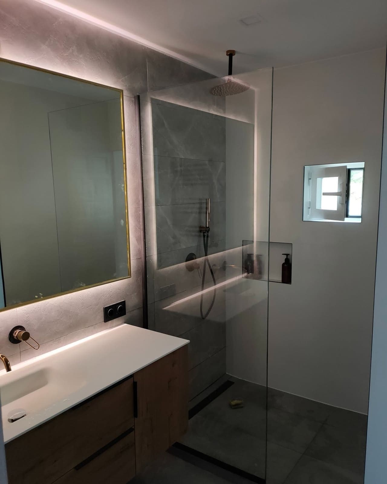 Reforma de baño en Gandía con ducha de obra, mampara fija, grifería empotrada y espejo con luz LED
